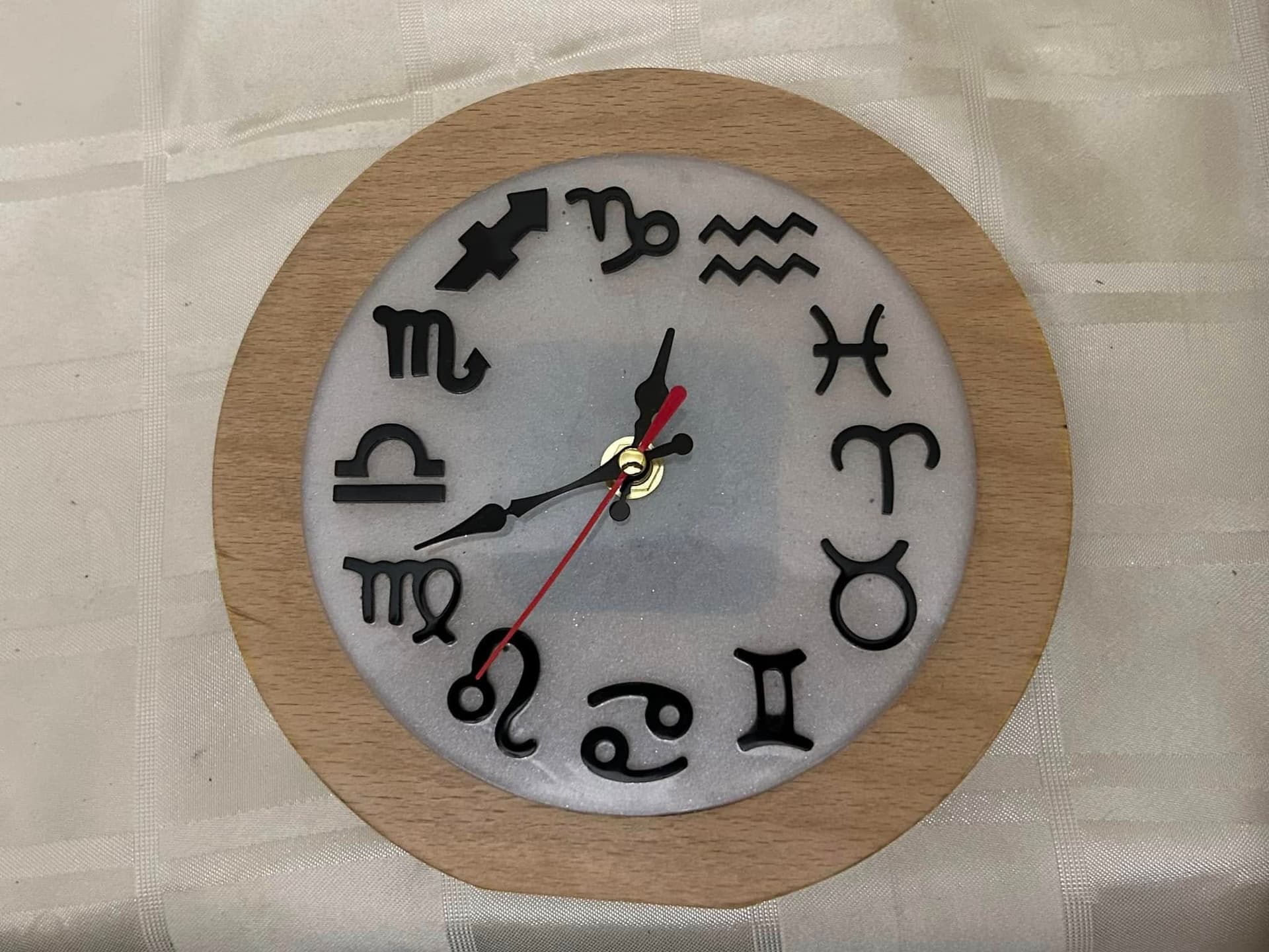 Round wall clock with carved zodiac symbols replacing numerals